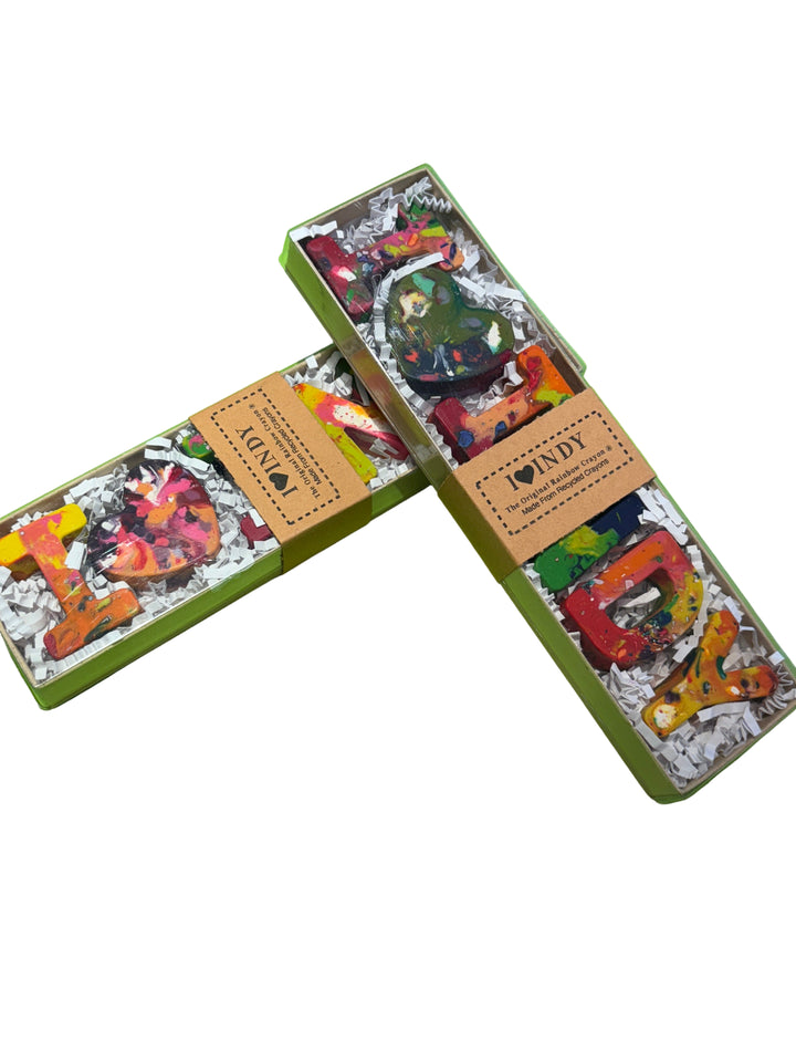 Three colorful soap bars in decorative boxes on a green surface