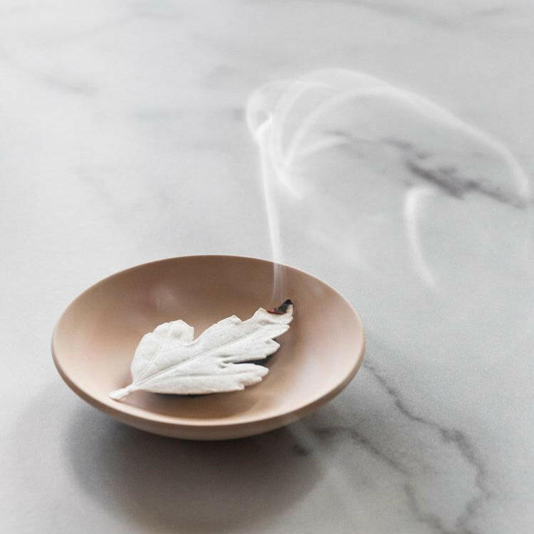 Bronze bowl with white feathers on a marble surface