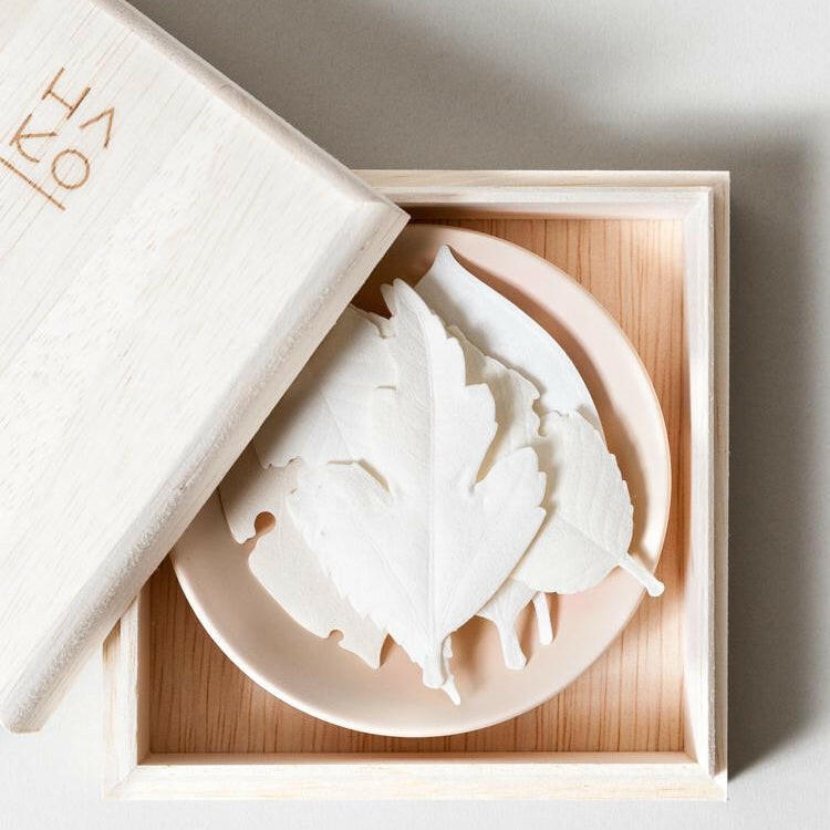 White soap bars in a wooden box with a white box labeled 'Kera' on a light gray background