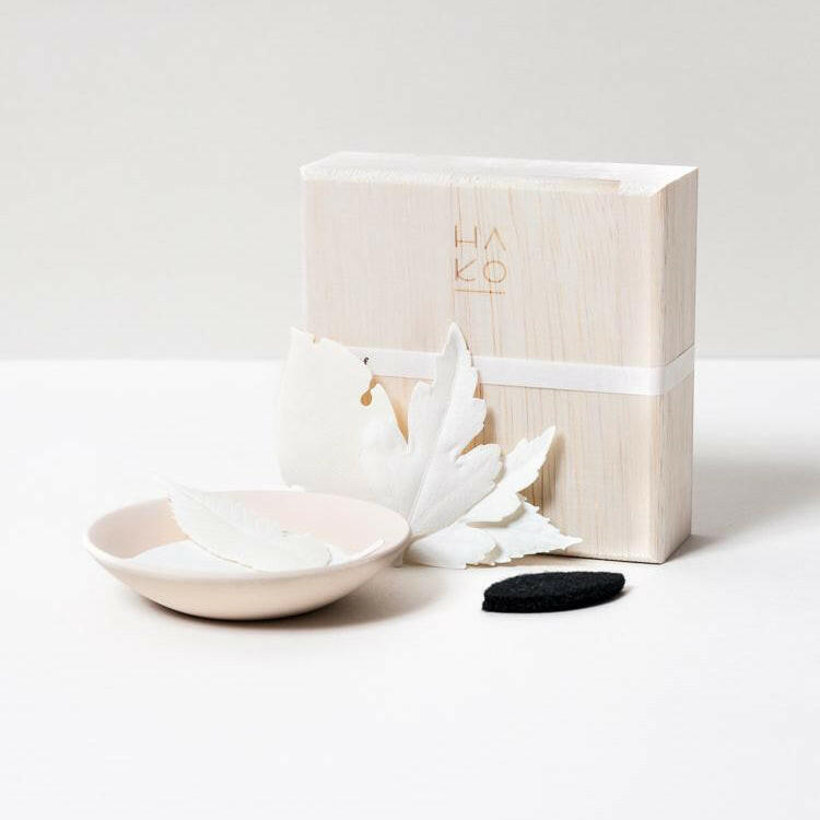 White ceramic dish with black stone and white box on a light gray background