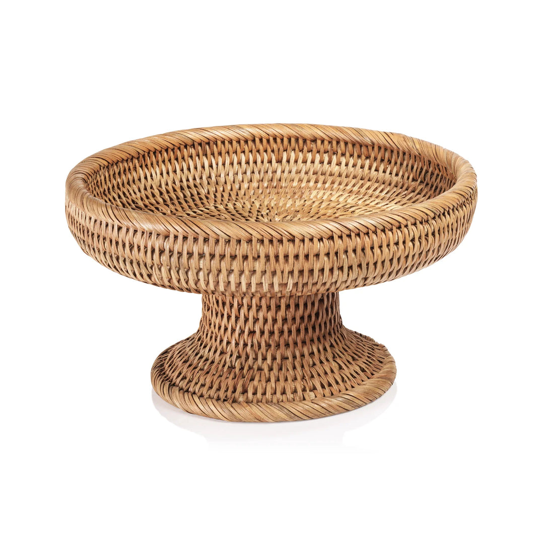 A round woven rattan pedestal table or stand with a natural light brown finish, shown on a clean white background | Artisans
