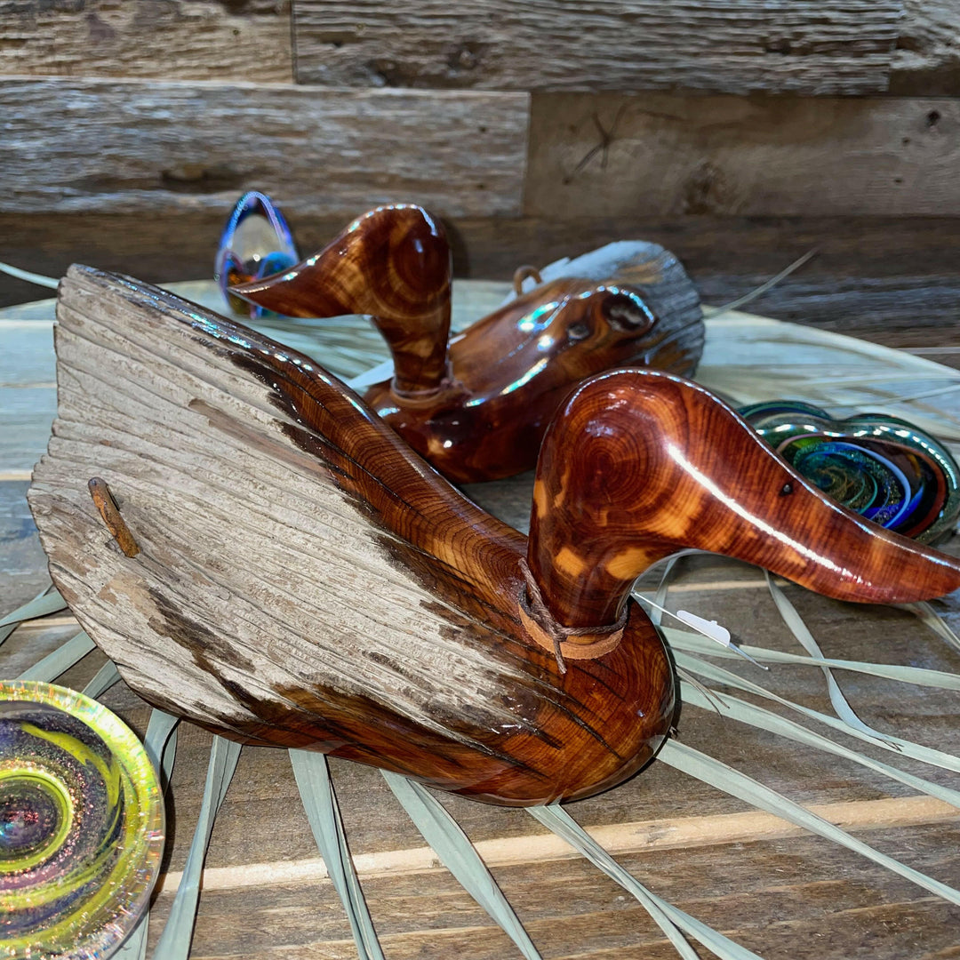 Wooden duck decoys on a woven surface with a wooden background