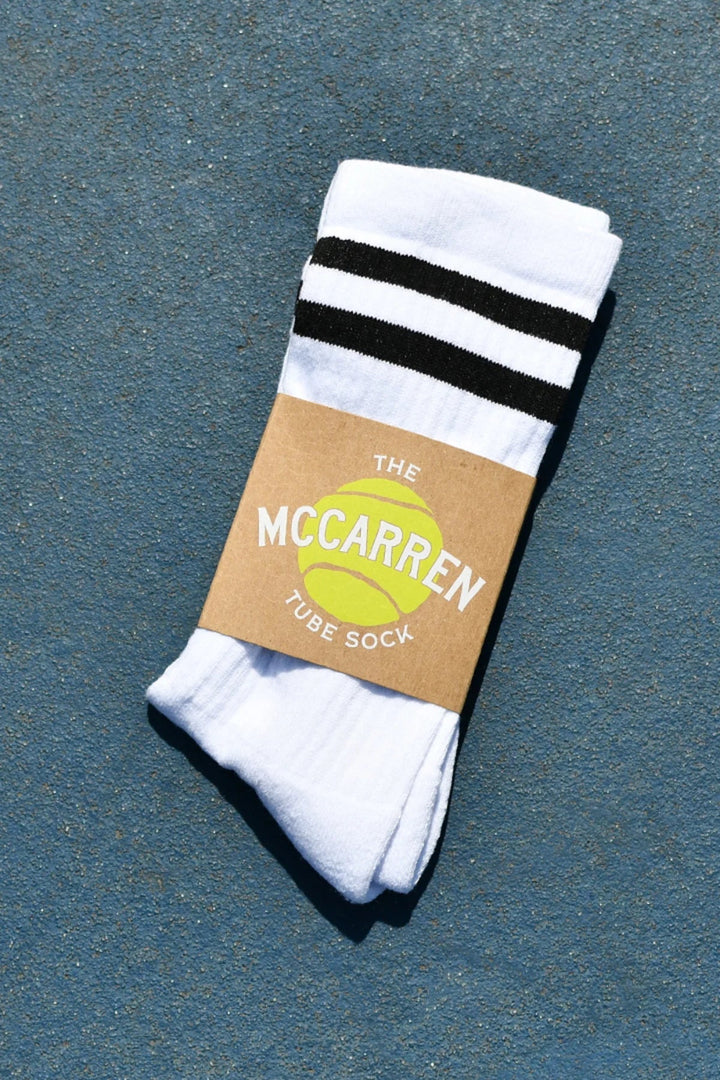 White tube sock with black stripes on a cardboard label against a blue background